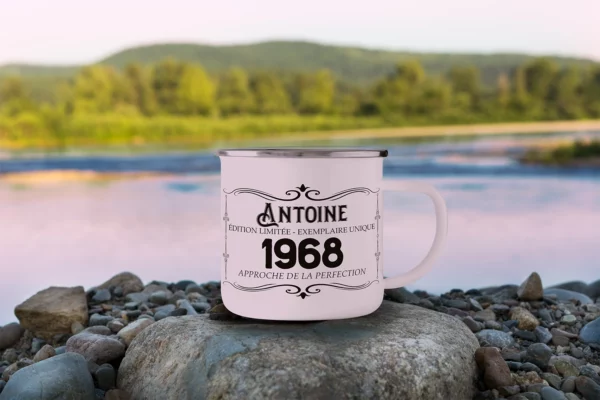 Mug en acier émaillé vintage sur des pierres au bord d'un fleuve