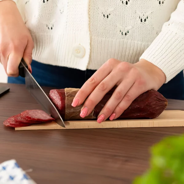 Femme coupant un saucisson sur la planche à découper